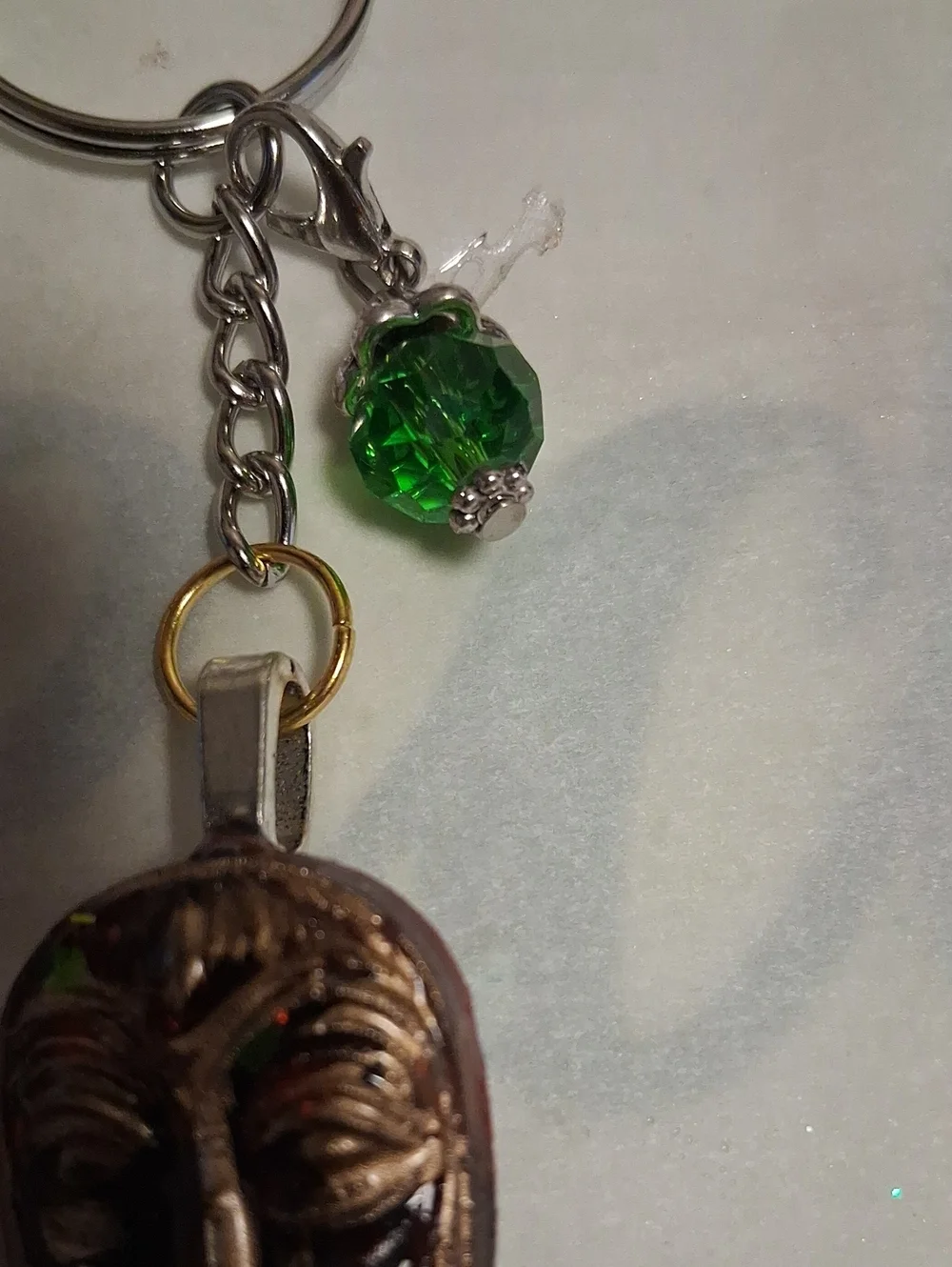 Artisan Bronze Mask Keychain with Green Crystal Accent
